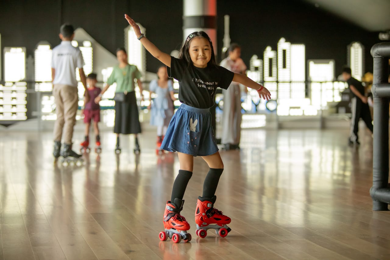 A girl balances on roller skates as families skate together behind her at Spin City