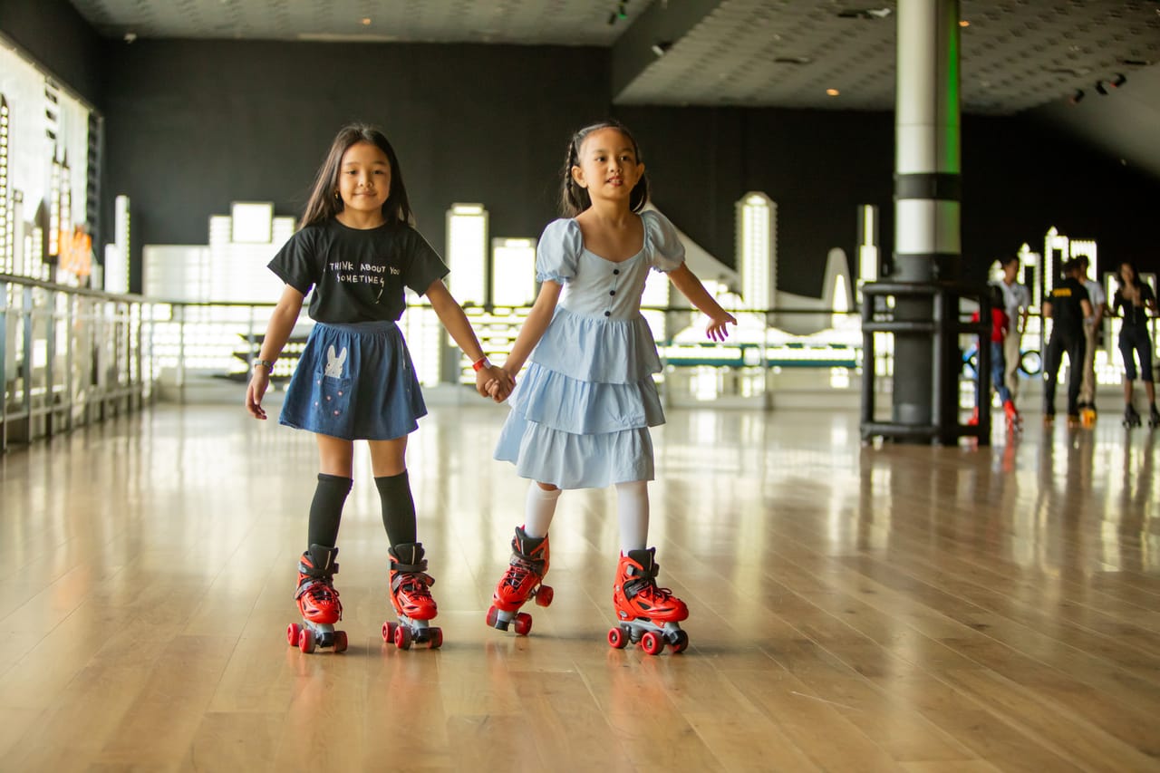 Two sisters smiling side by side on red roller skates at Spin City roller rink, Limketkai Center